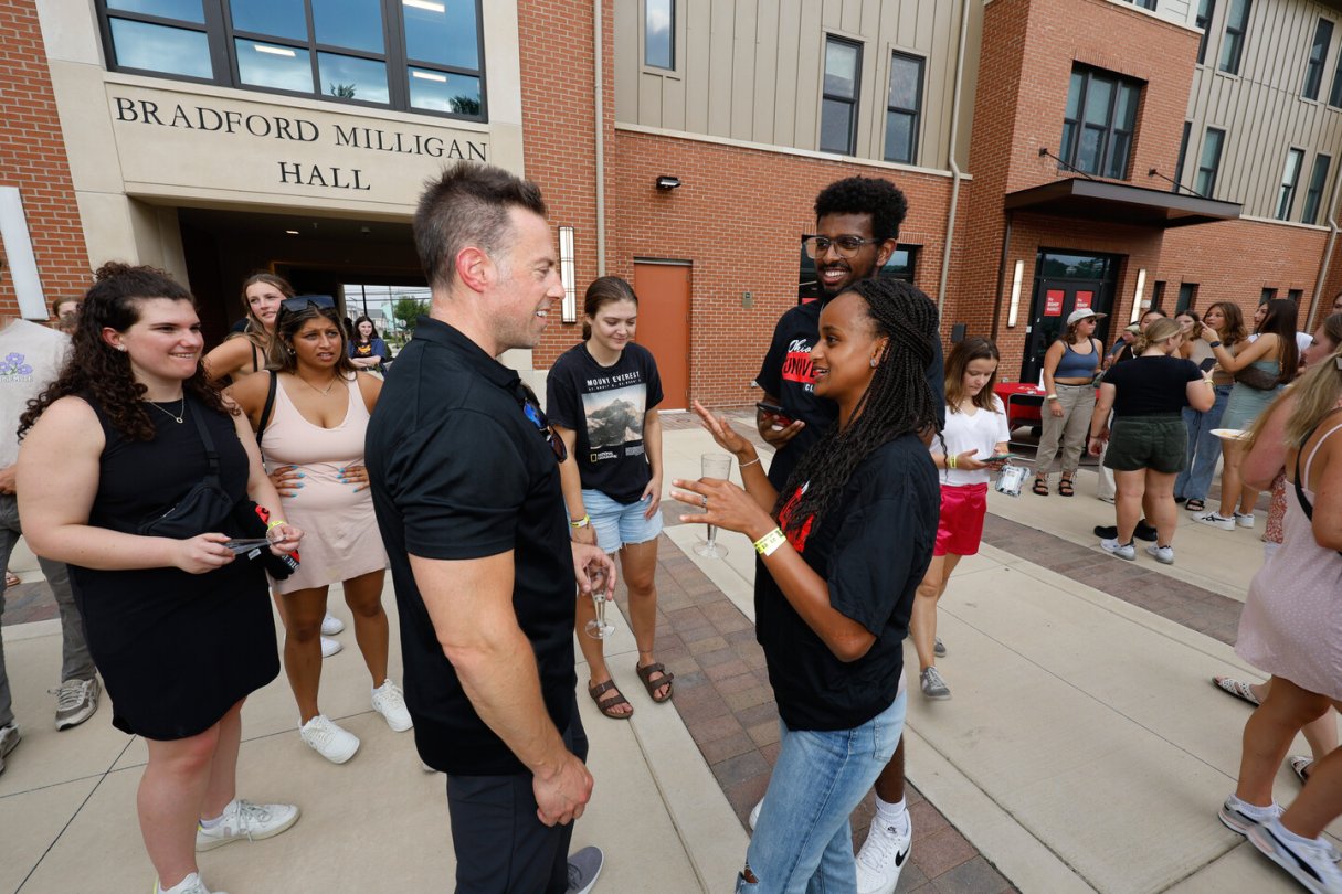 college president speaking with students outside of a campus building